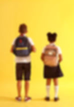 A boy and a girl wearing backpacks with their backs to the camera