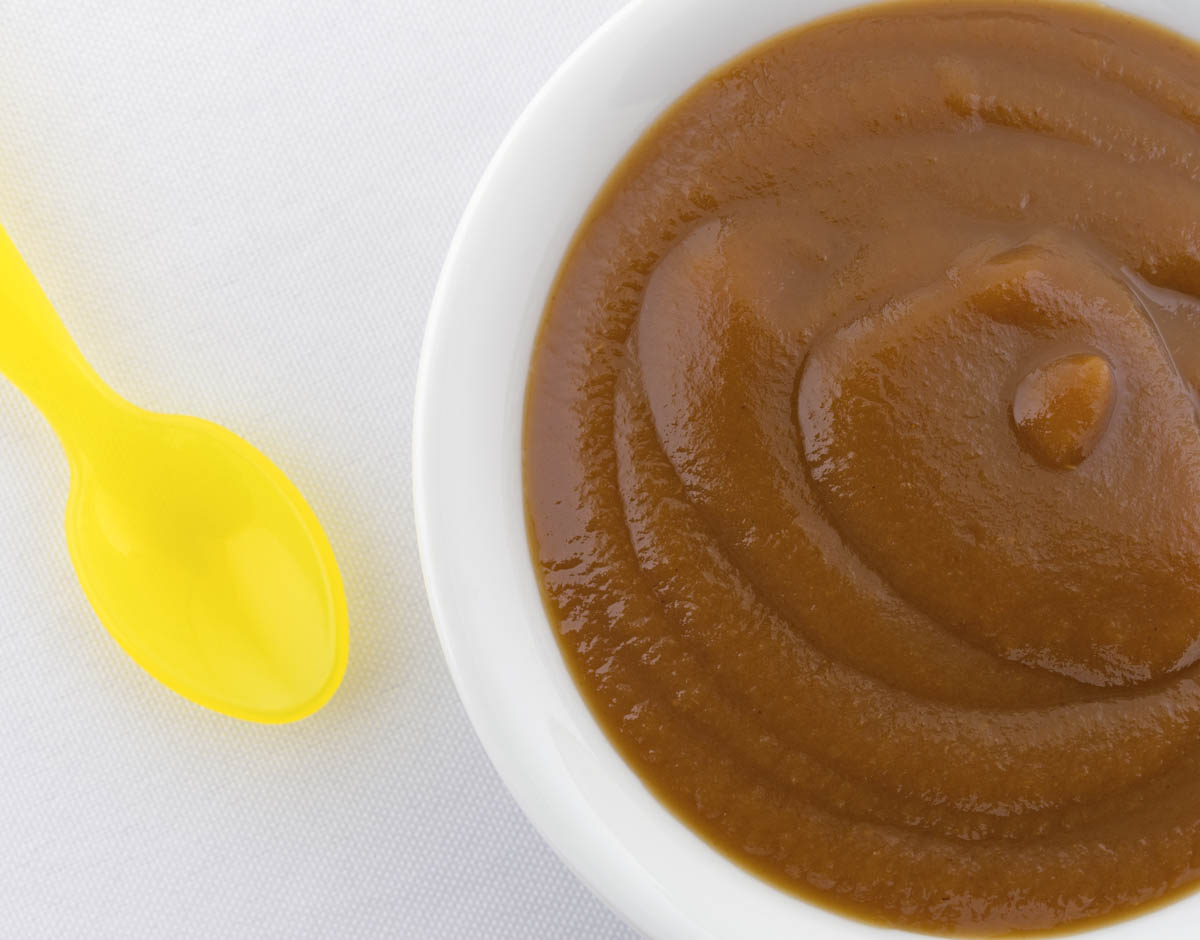 Prune baby food puree served in a white bowl.