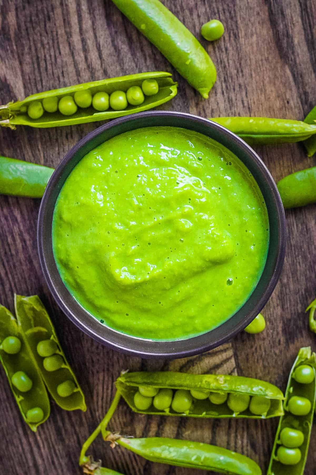 Baby food with peas in a black serving bowl.