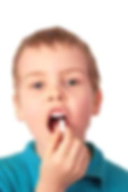 a boy attempting to swallow a large capsule pill