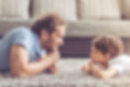 Dad and son lying on the carpet having a staring contest