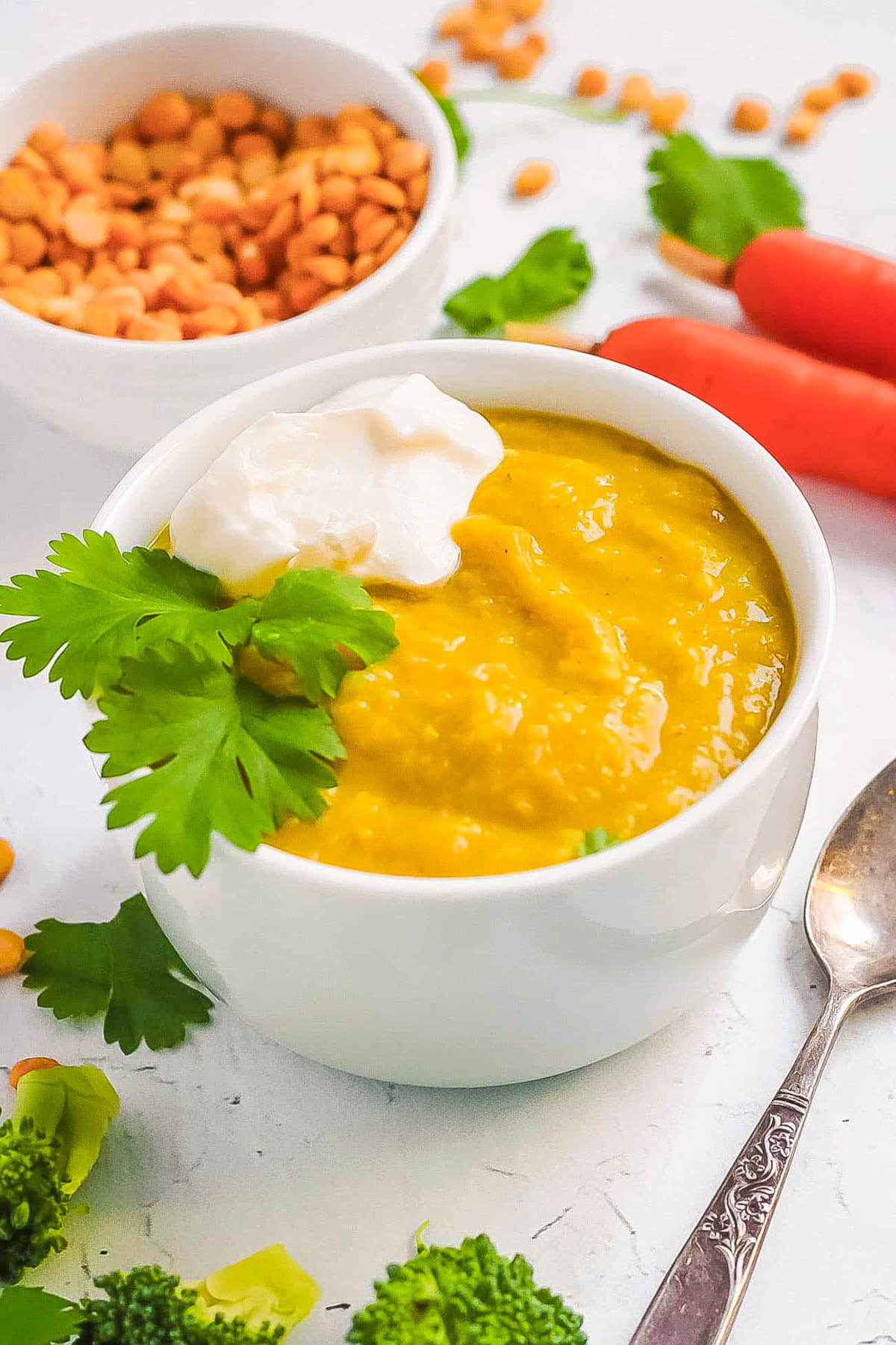 Lentils for baby served in a white bowl with some fresh herbs and veggies on the side.