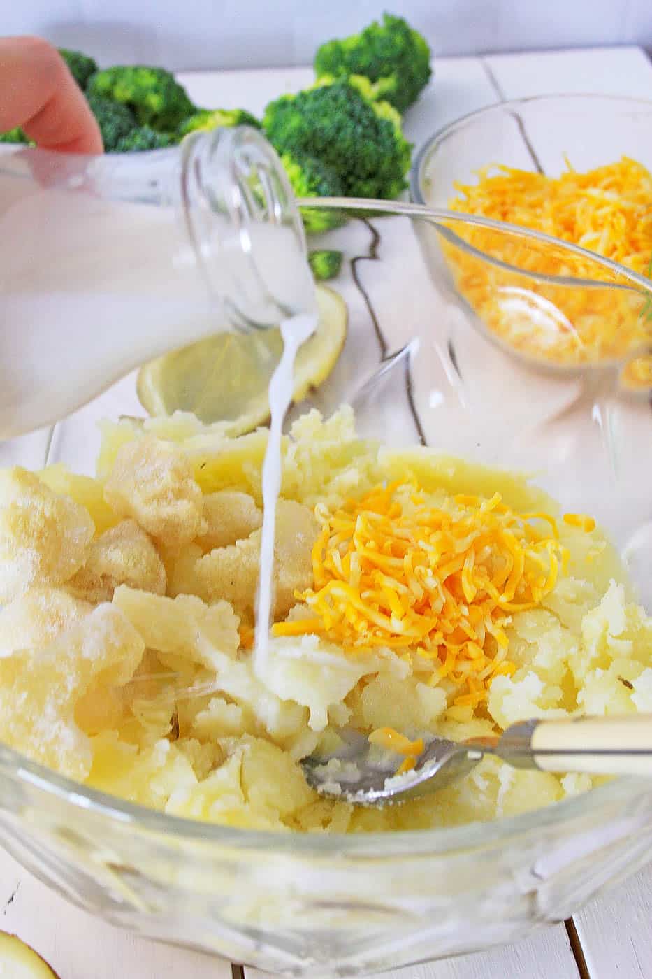 potatoes and buttermilk and cheese being mixed in a bowl