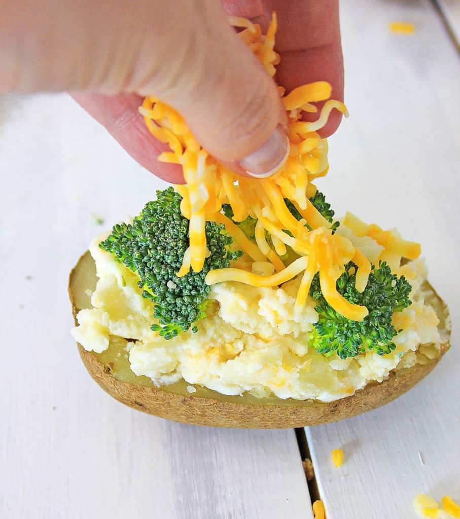 vegetarian baked potato being topped with broccoli and cheese