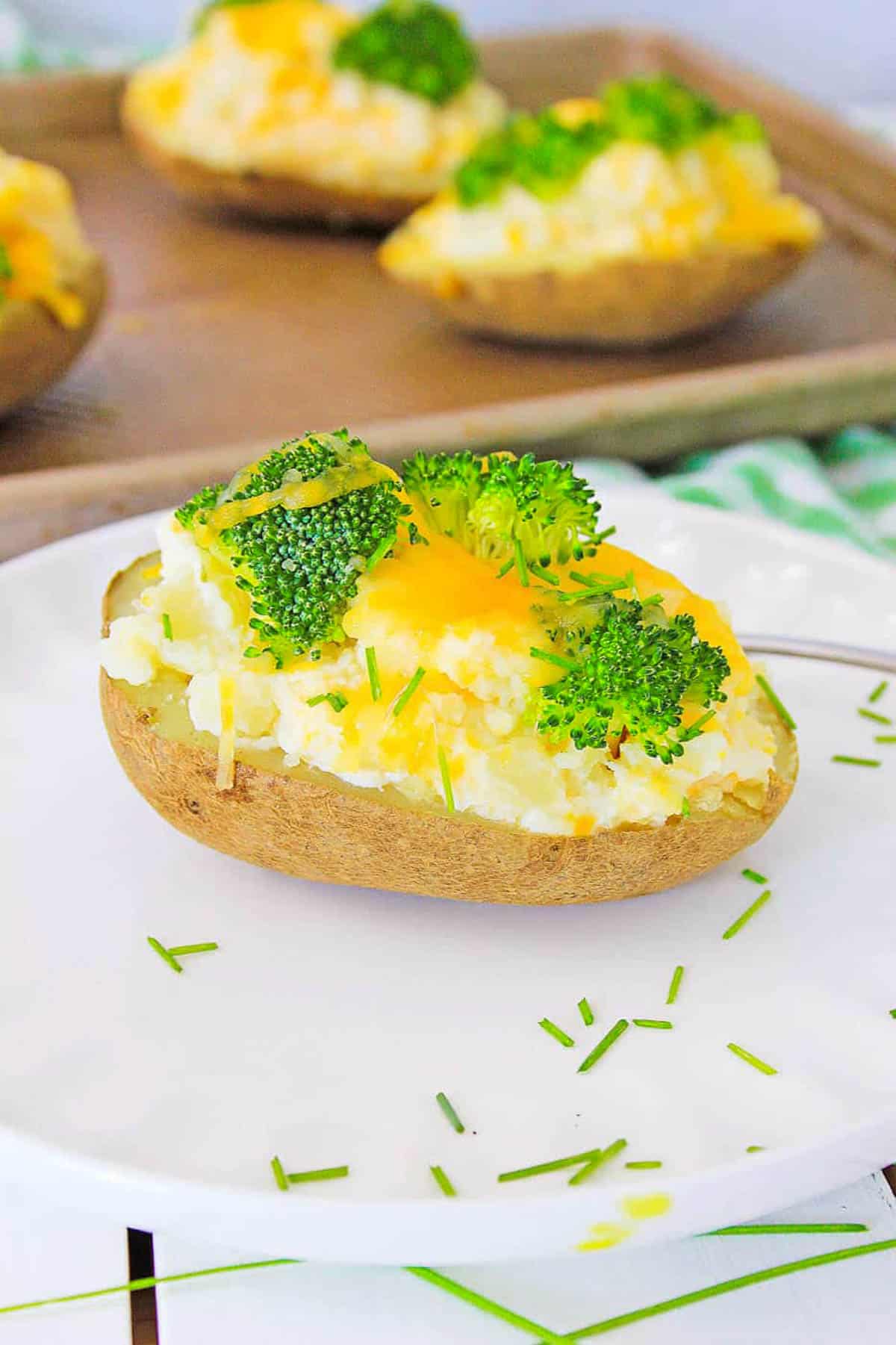 Healthy baked potatoes topped with broccoli and cheese, served on a white plate.