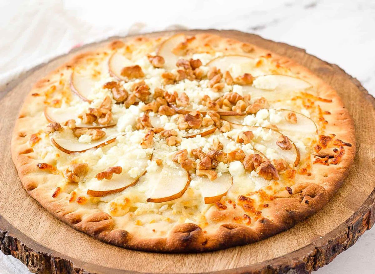 Pear walnut gorgonzola pizza served on a wood cutting board.